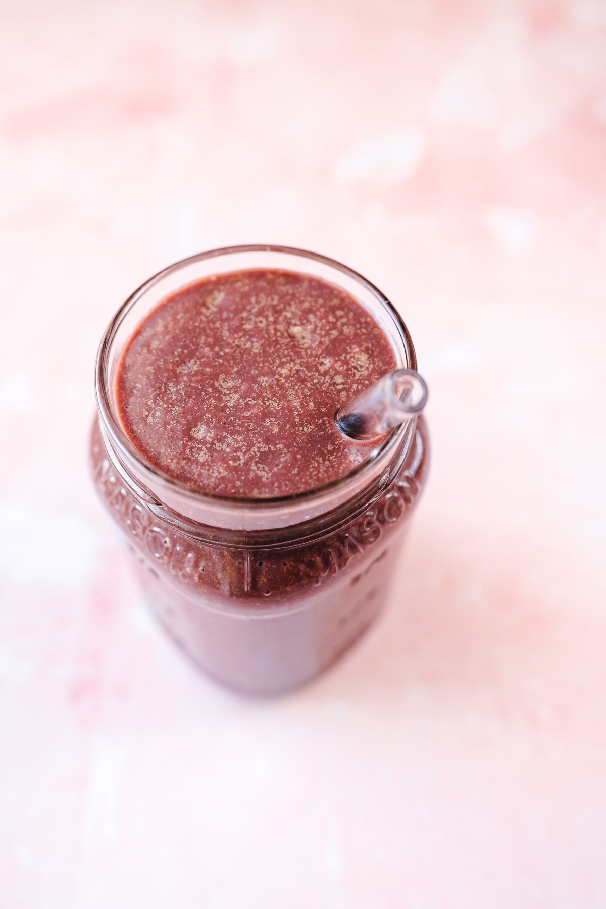 A dark purple smoothie in a glass jar.