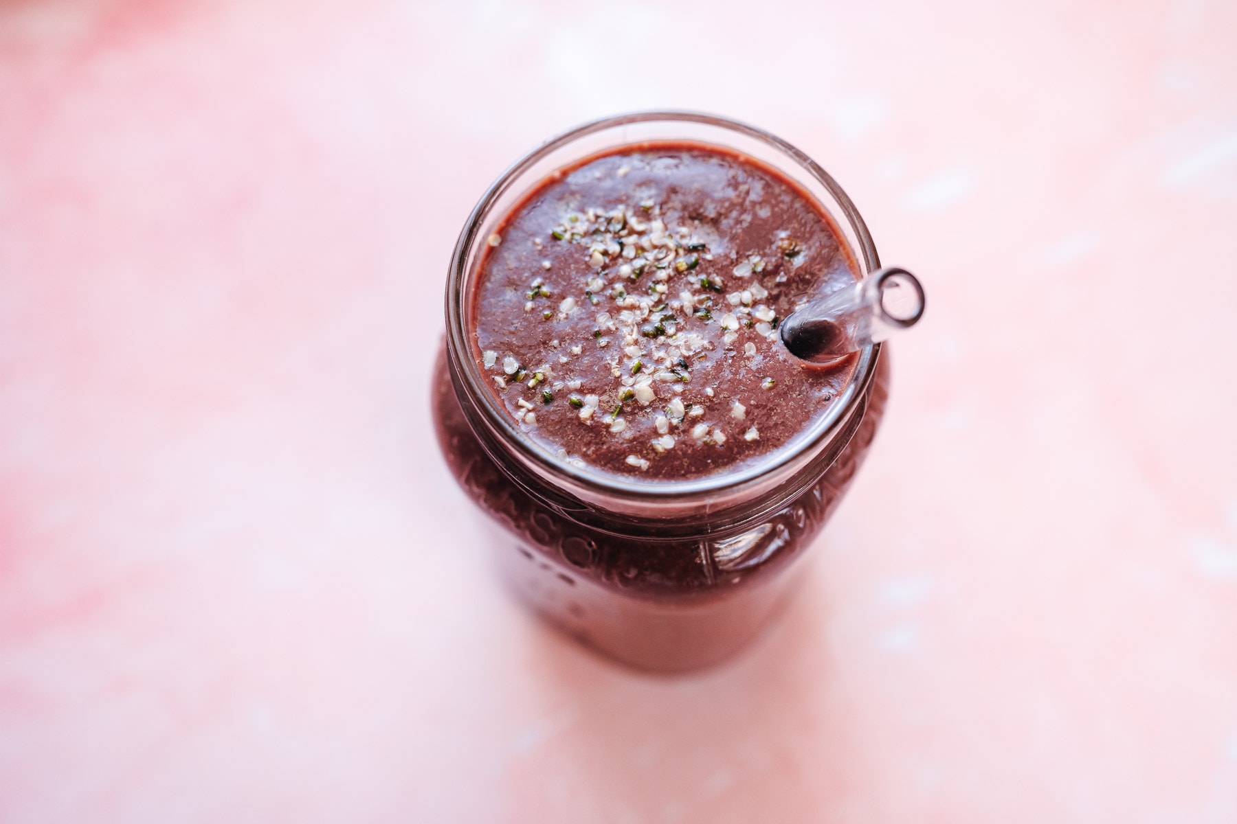 A Mason jar filled with purple smoothie sprinkled with white seeds.