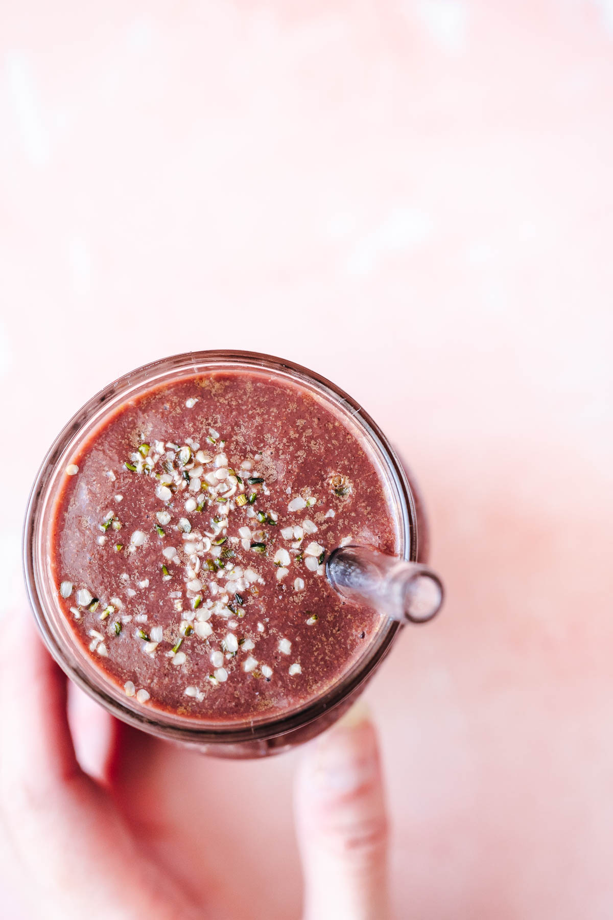 A hand holding a glass filled with a purple smoothie.