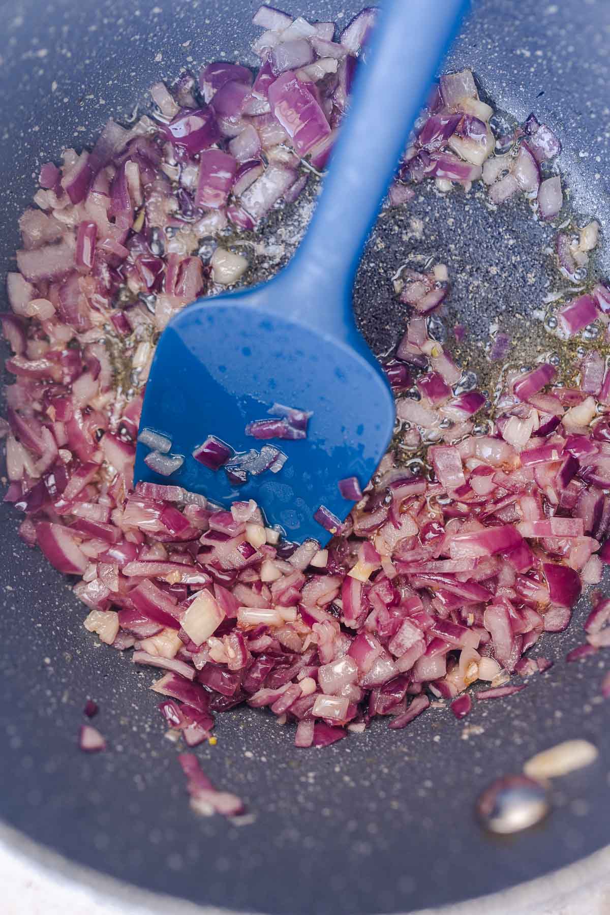 A pot filled with sauteed red onion.