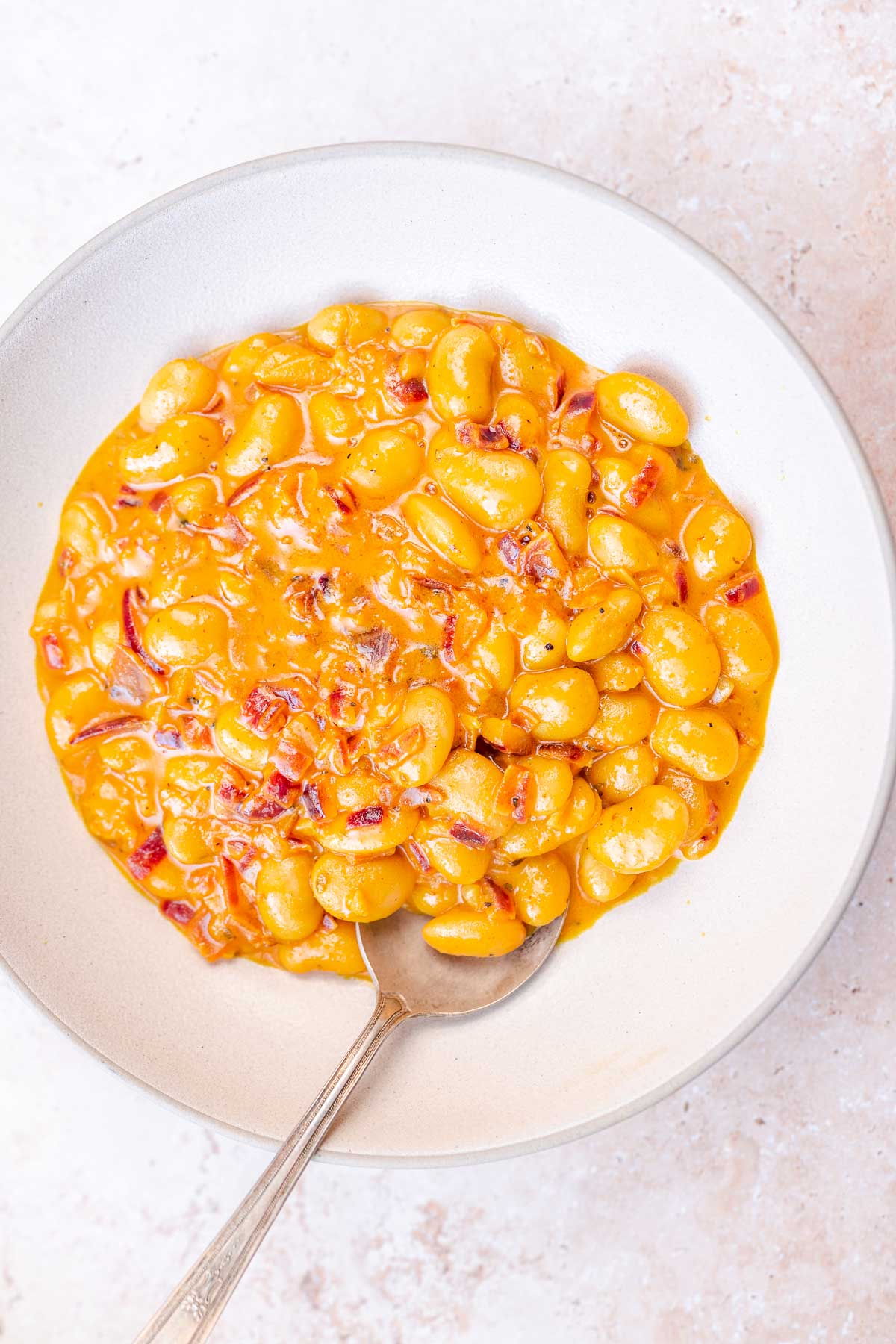 Top view of a tan ceramic bowl filled with yellow cooked butter beans.