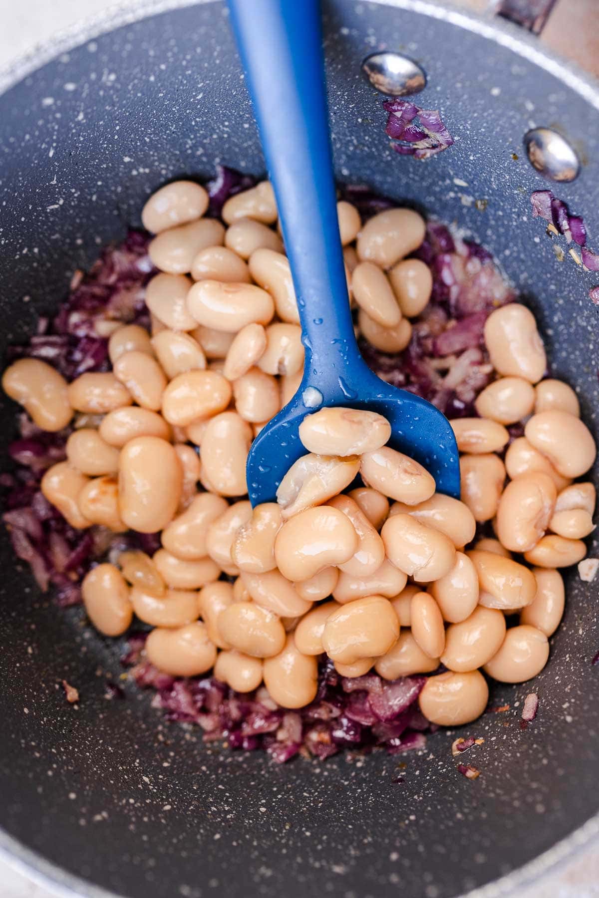 Butter beans and onions in a pot.