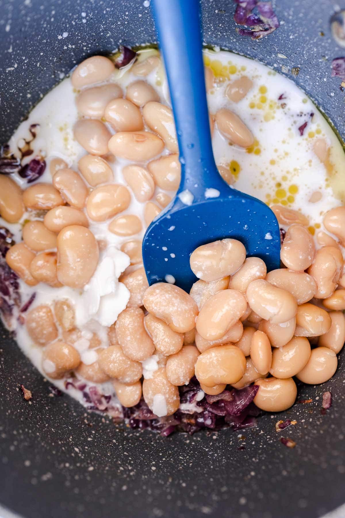 Butter beans, onion and coconut milk in a pot.