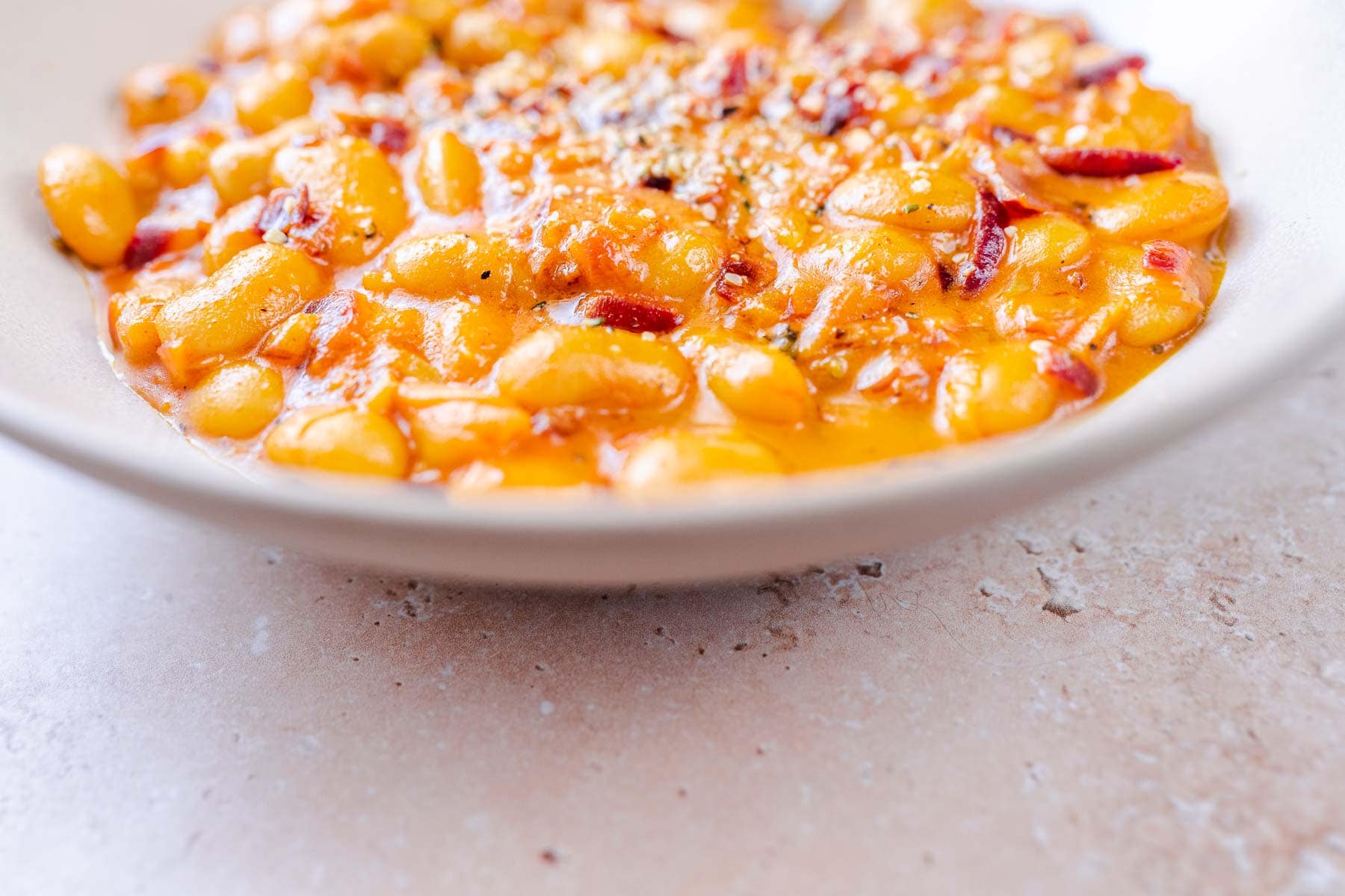 A tan ceramic bowl with cooked beans.