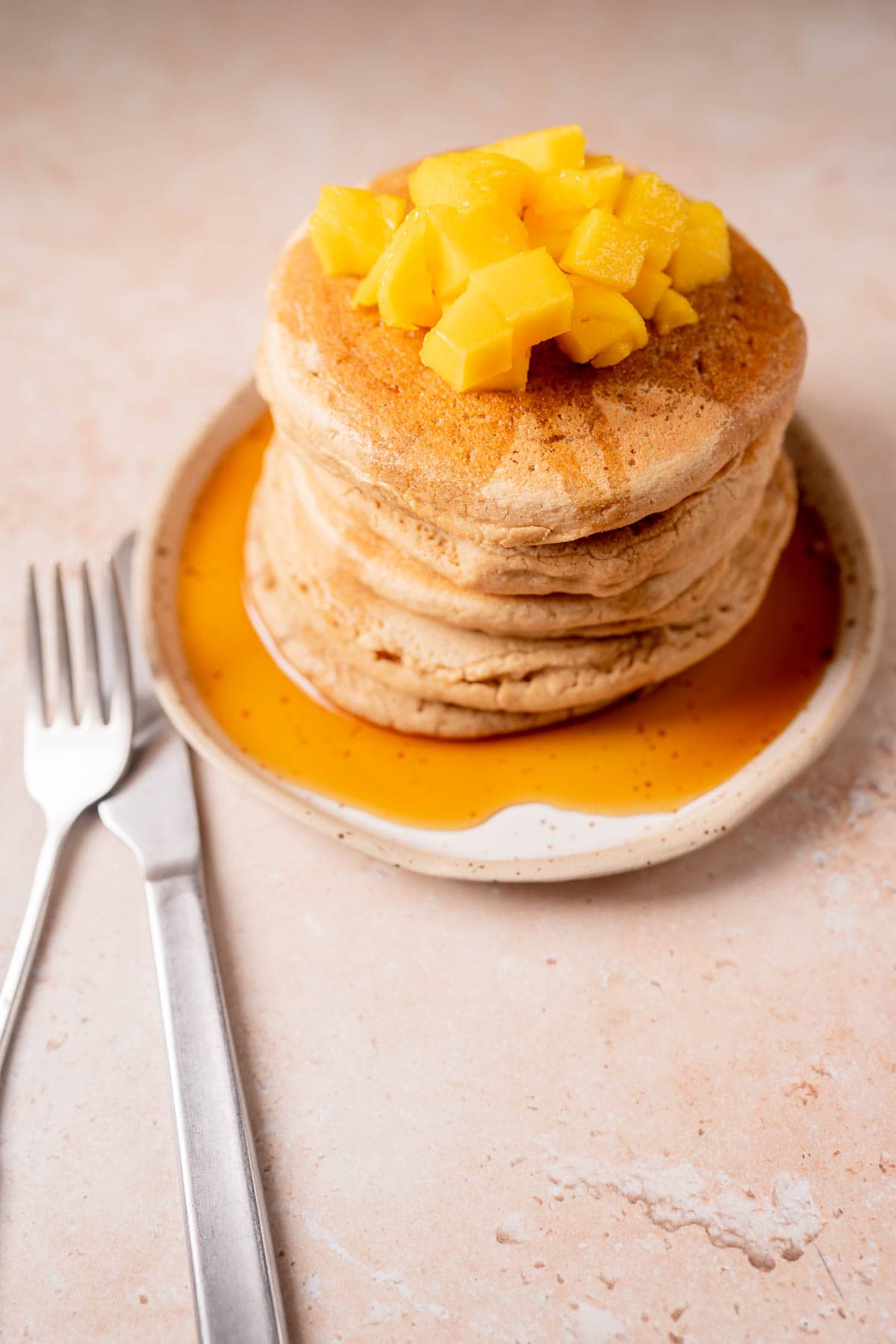 A stack of pancakes resting on a speckled ceramic plate.