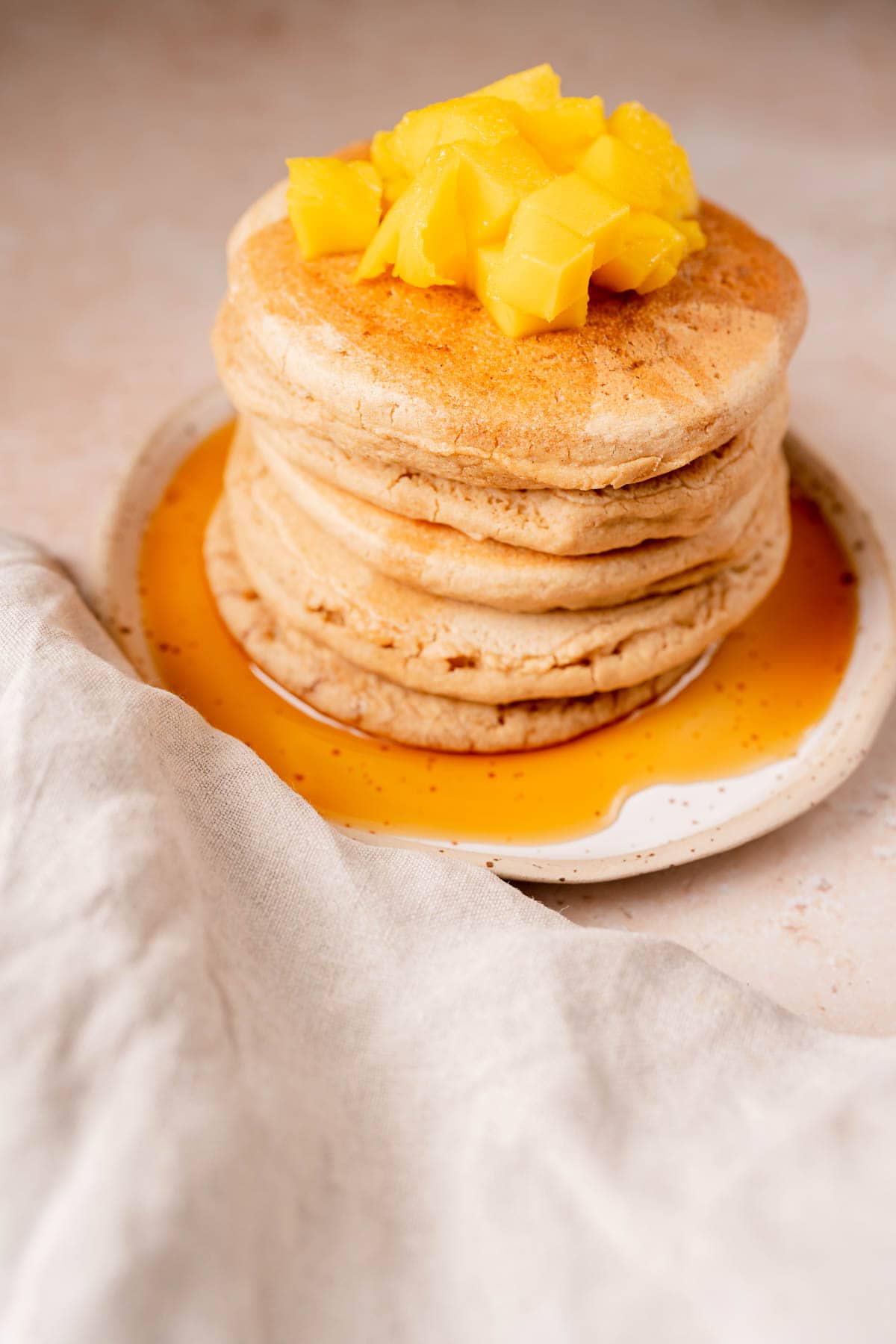 A stack of oat pancakes on a plate drizzled with syrup.