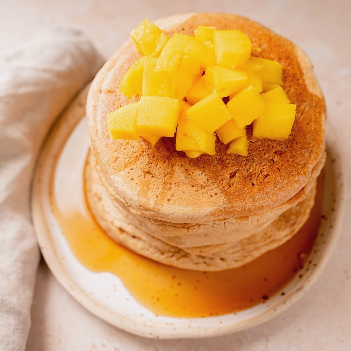 A stack of pancakes topped with fresh chopped mango.
