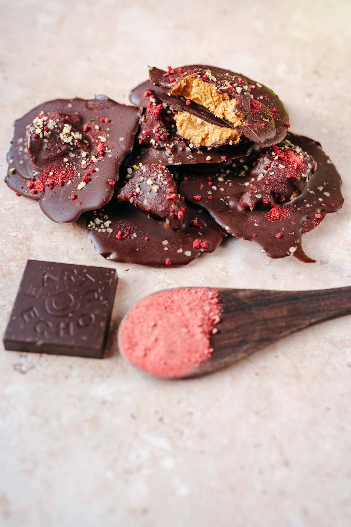 A pile of homemade chocolate puddles dusted with pink powder and small seeds.