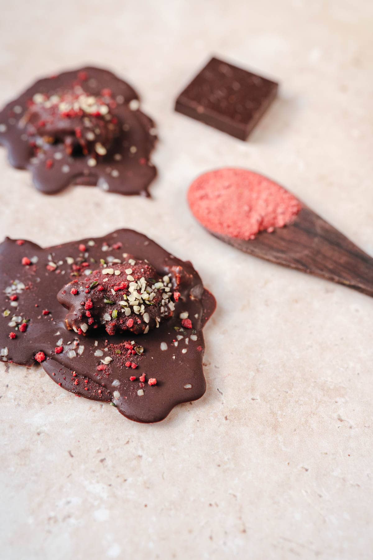 A close shot of a chocolate puddle topped with small hemp seeds and a dusting of pink strawberry powder.