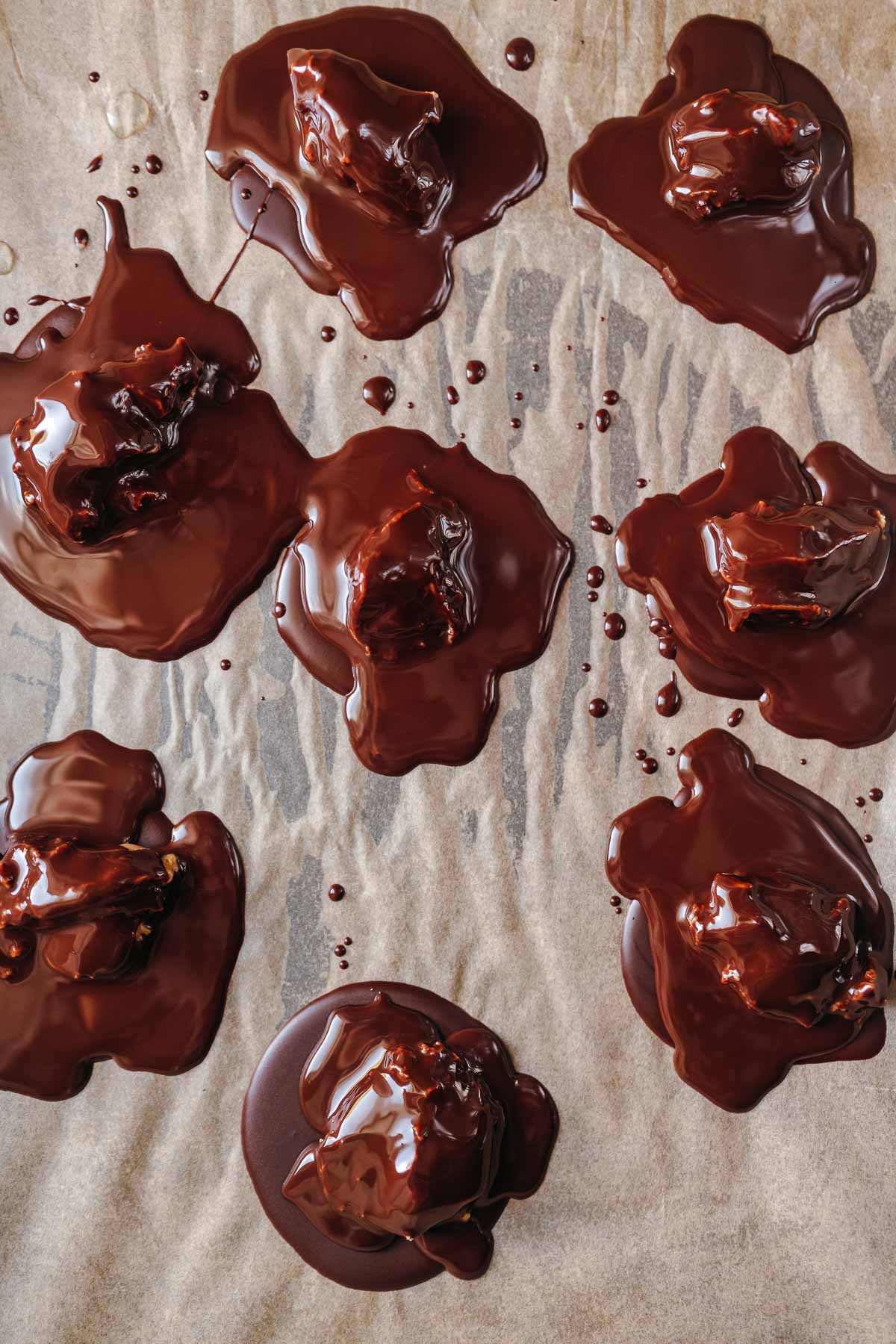 Melted puddles of chocolate on tan parchment paper.