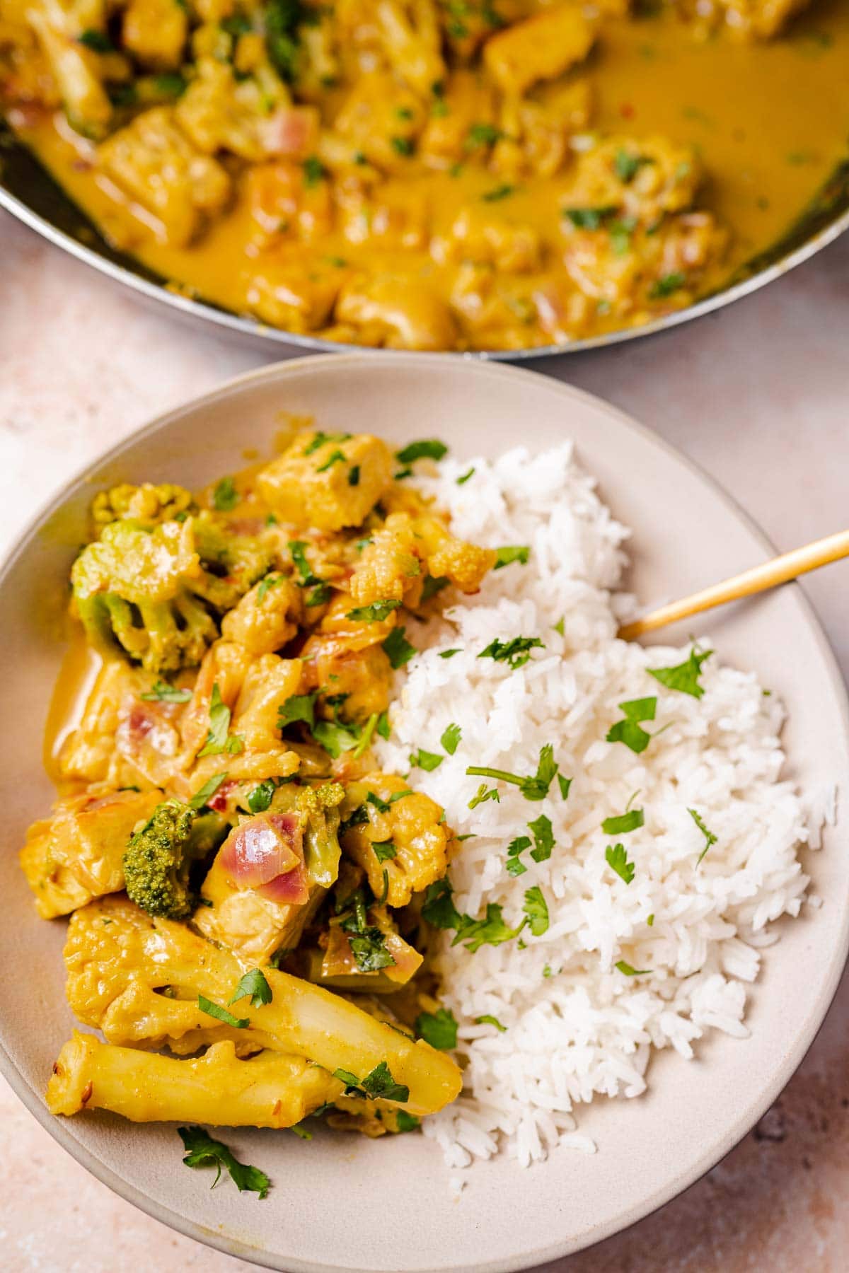 A large bowl of yellow curry over white rice with a gold spoon.