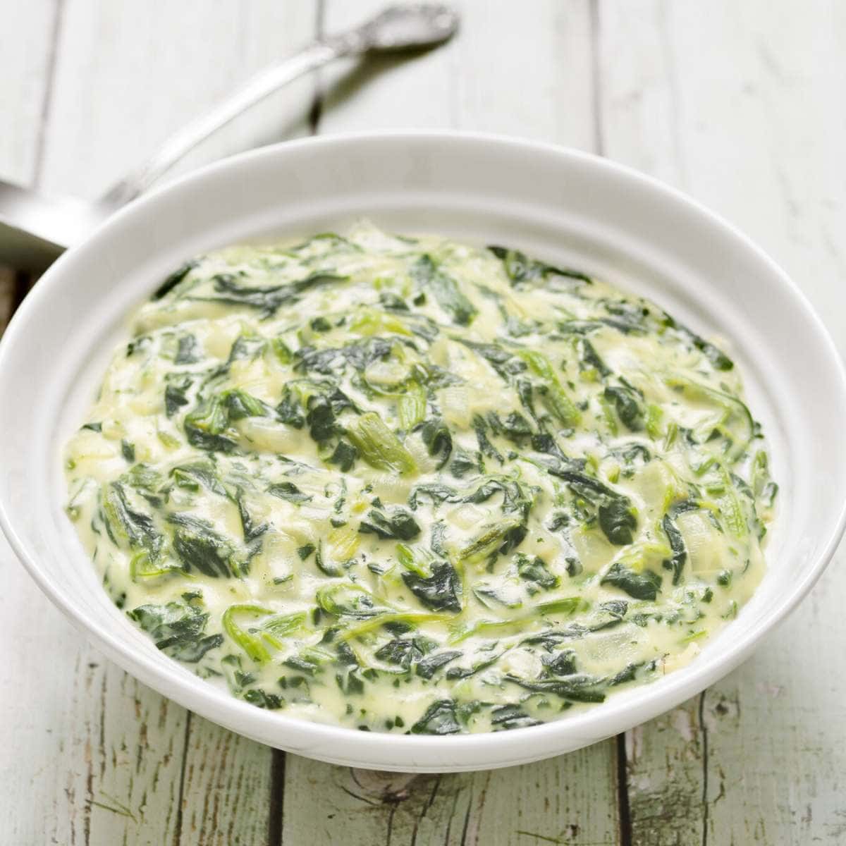 A white bowl filled with creamed spinach.