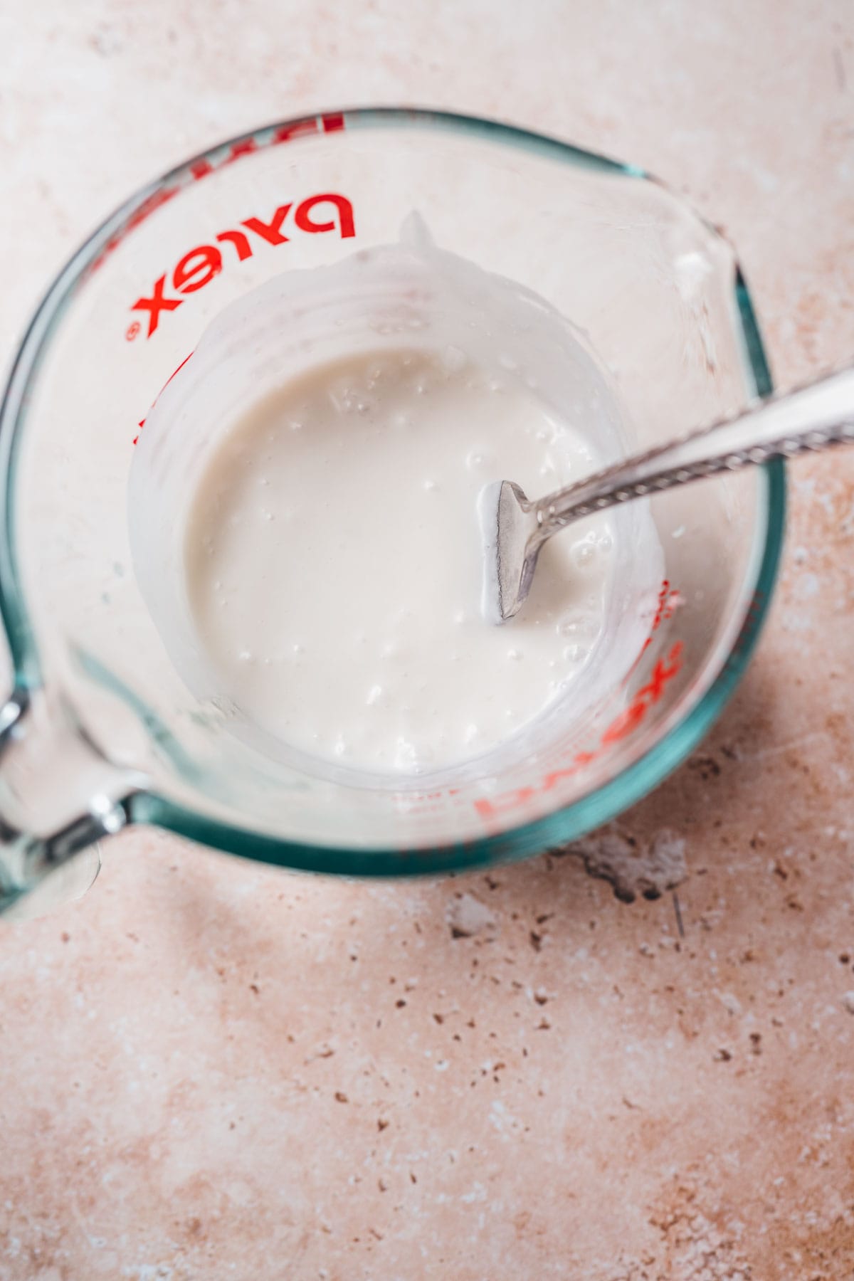 A measuring bowl filled with white milk and a silver fork.
