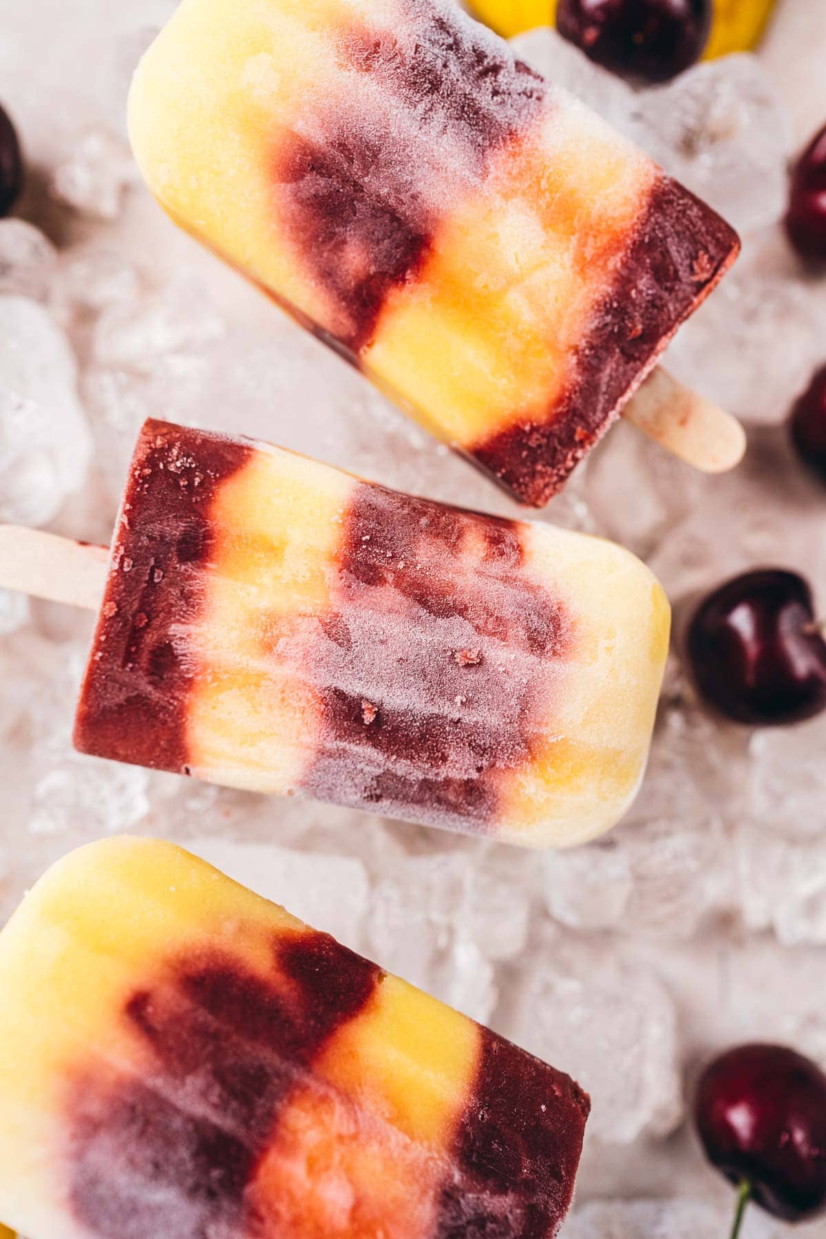Close shot of layered cherry mango ice cream pops.