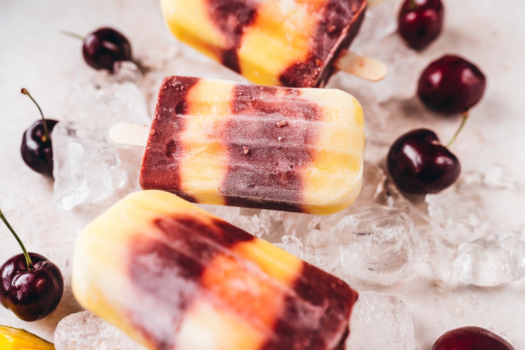 Close shot of homemade cherry ice pops resting on ice.