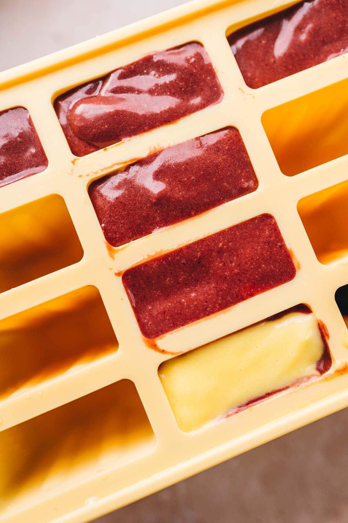 Yellow popsicle molds filled with ice pop mixures.