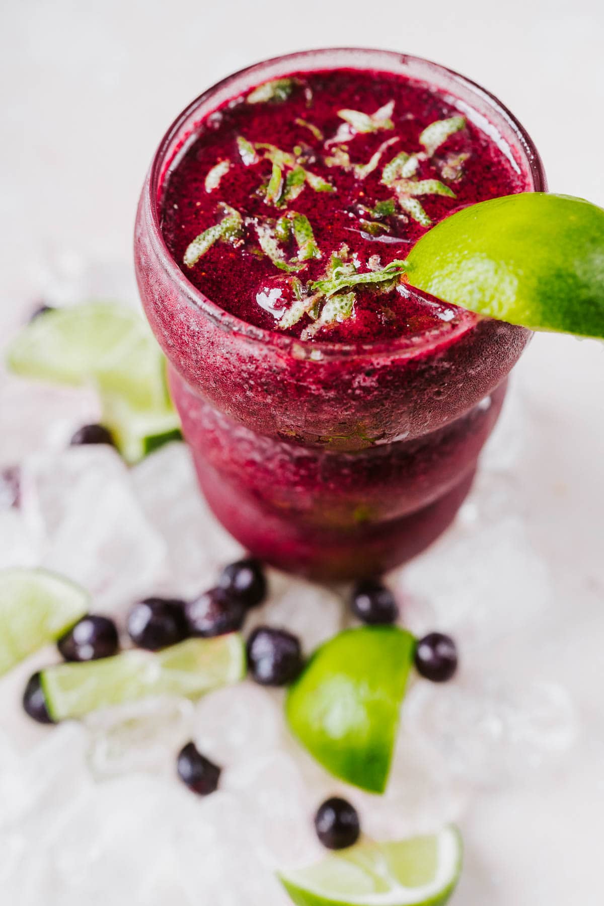 Top view of a homemade blueberry margarita garnished with fresh lime zest.