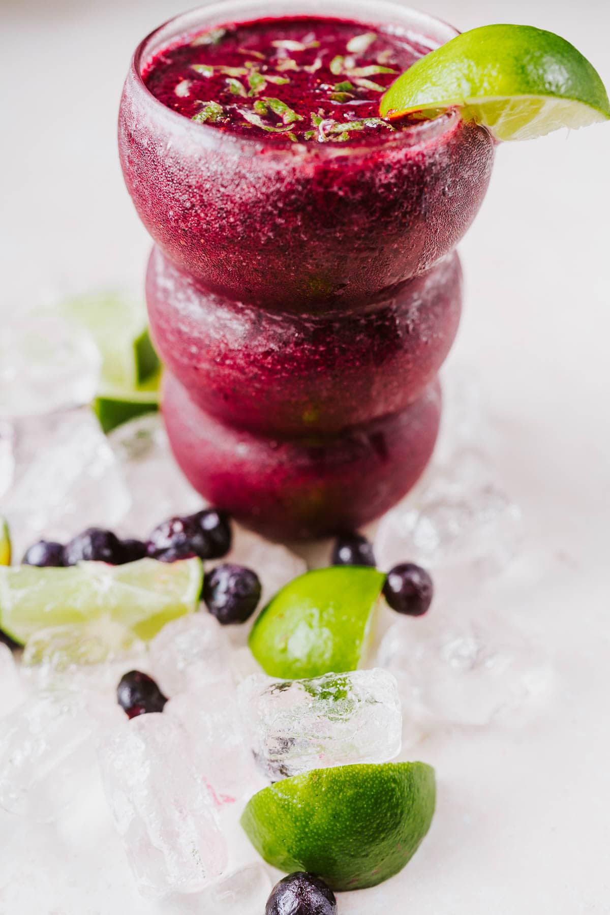 A tall clear glass filled with a homemade frozen mocktail garnished with lime.