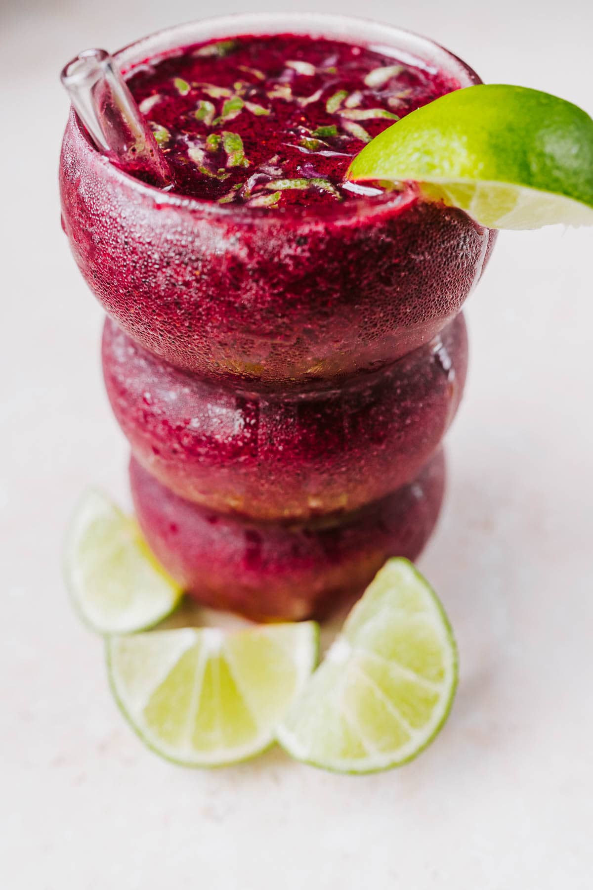 Close view of a tall glass filled with a purple frozen beverage.