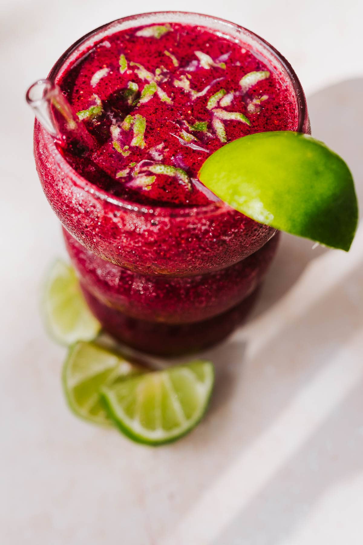 Top view of a frosty beverage garnished with lime zest and lit by the sun.