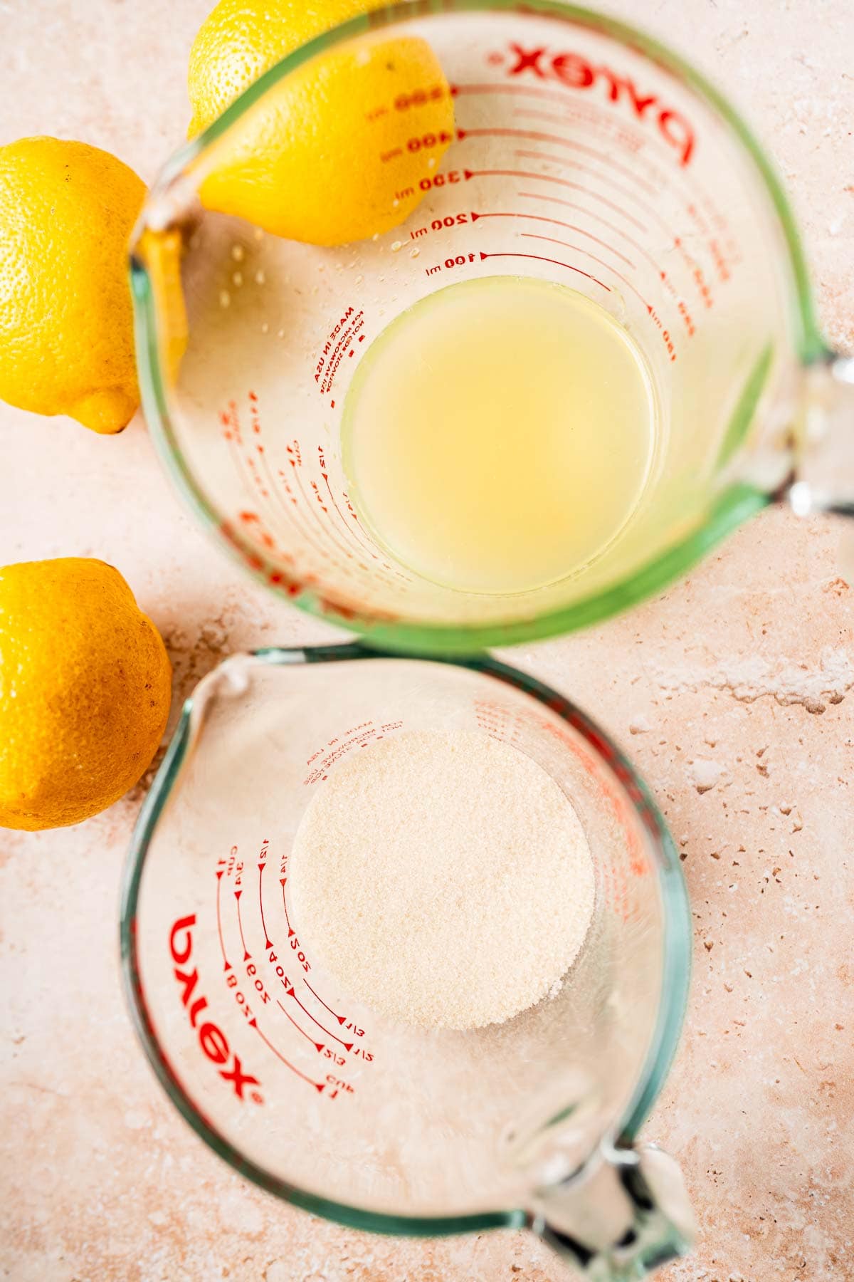 Top view of two pyrex measuring cups filled with sugar and lemon juice.