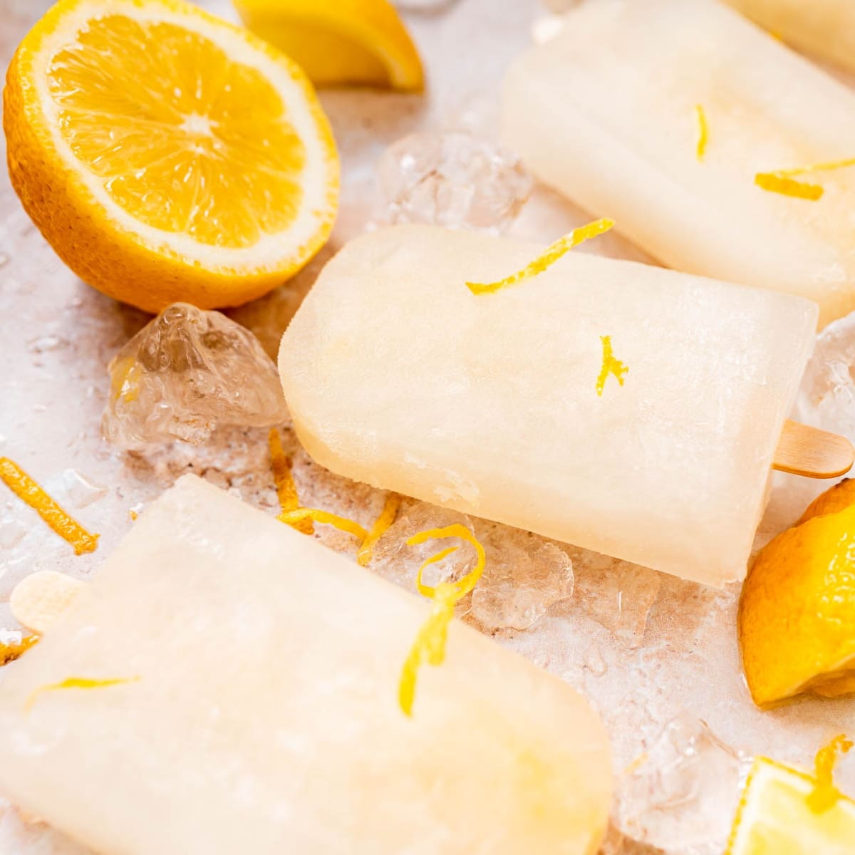 A close shot of homemade lemonade popsicles resting on table covered in ice.