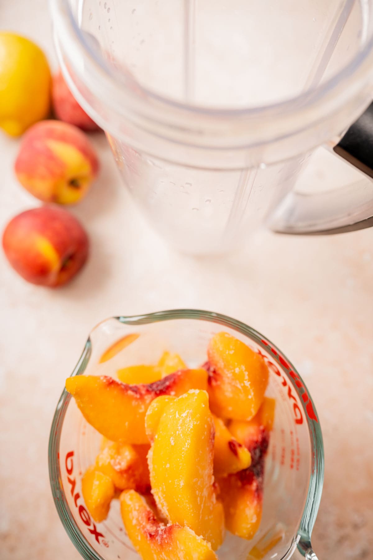 Top view of a blender container filled with peaches.