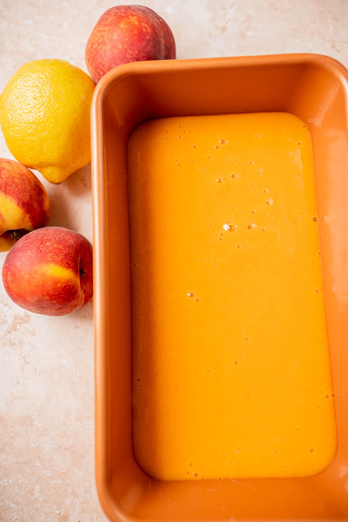 Top view of a loaf pan filled with a homemade peach sorbet mixture.