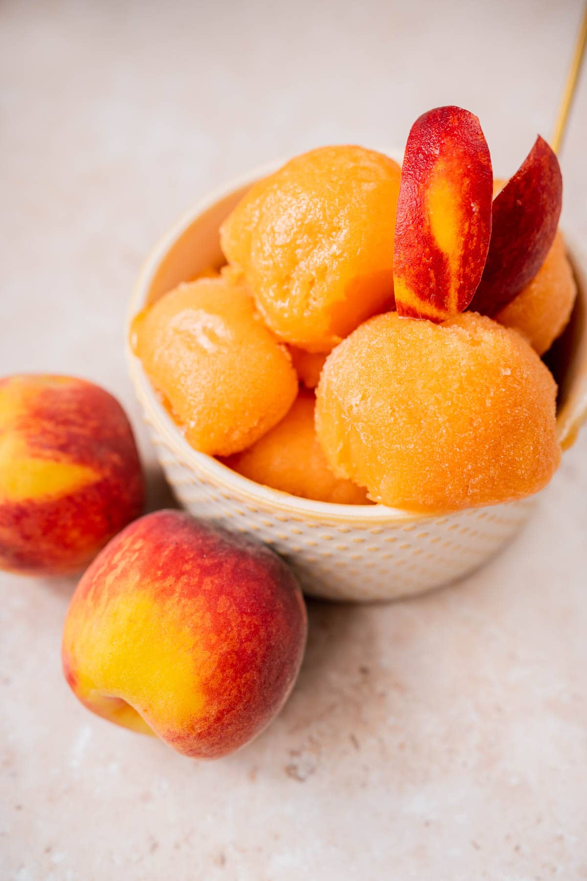 Close shot of a tan bowl filled with scoops of homemade peach sorbet.