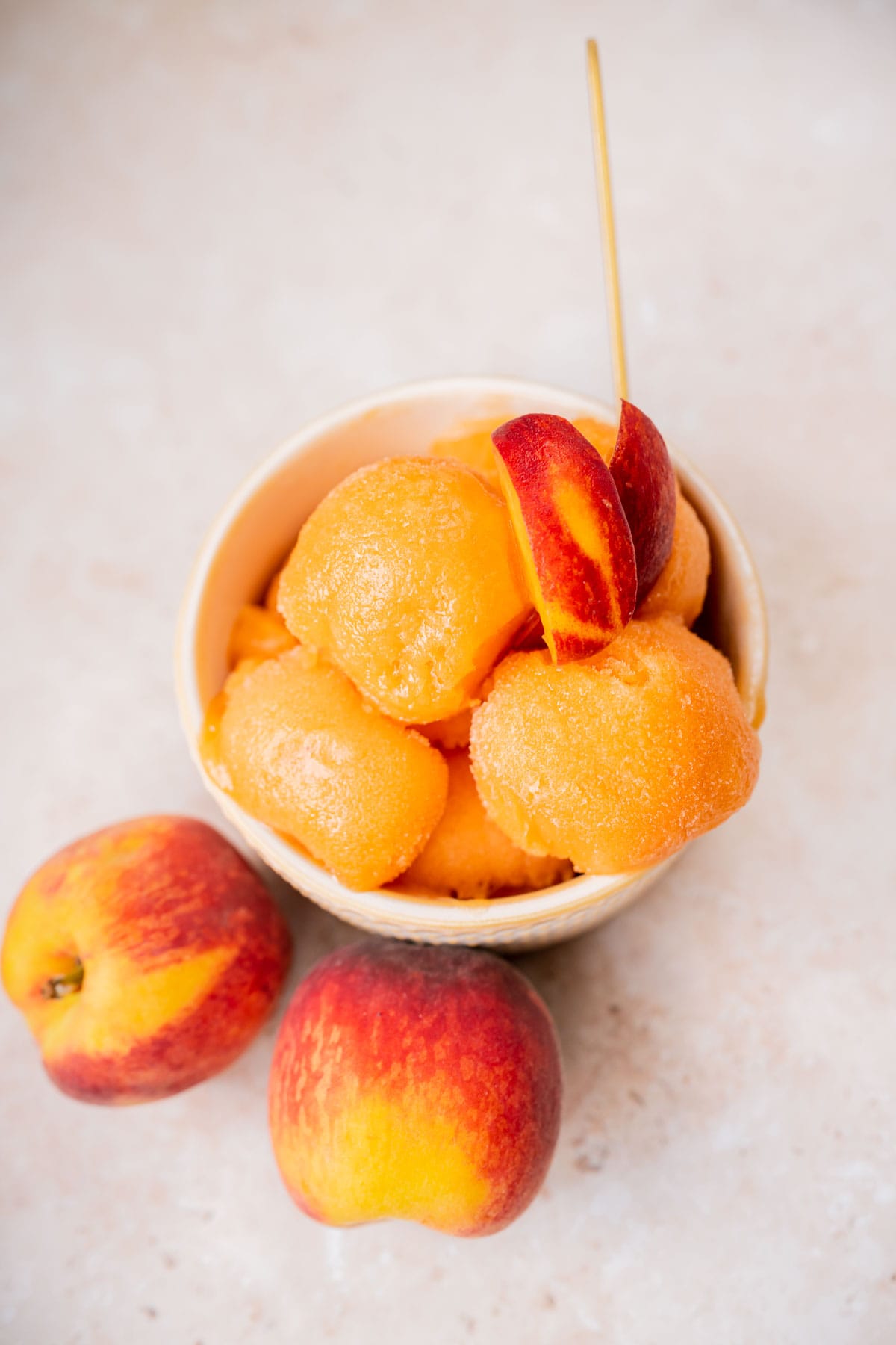 Top view of a small bowl filled with peach sorbet garnished with peach slices.