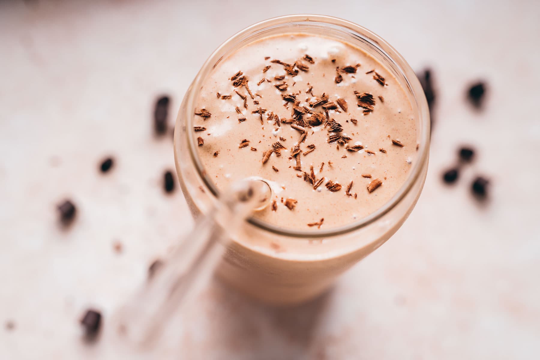 A clear glass filled with a tan shake topped with chocolate curls.