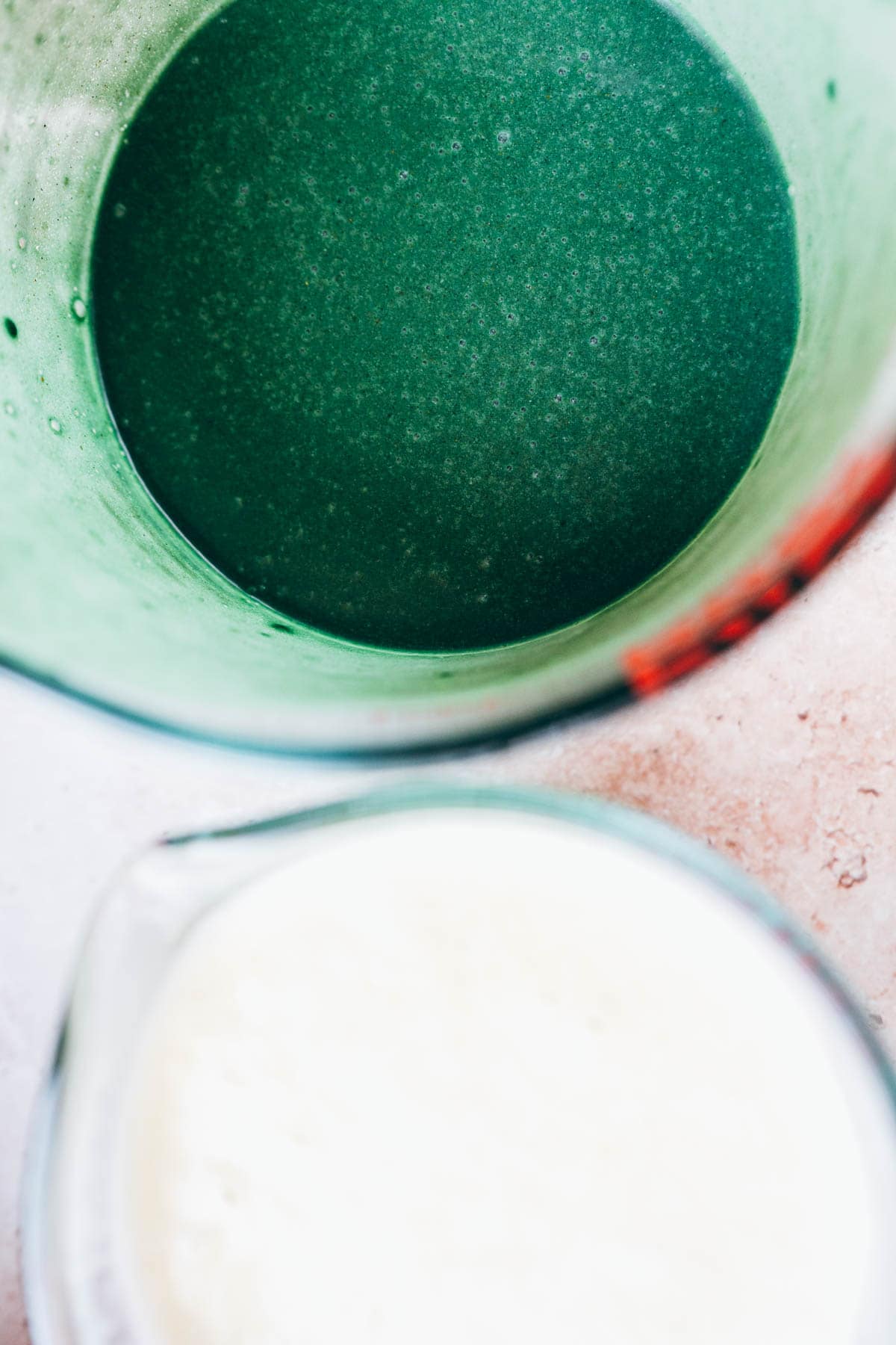 Two measuring cups filled with blended popsicle ingredients.