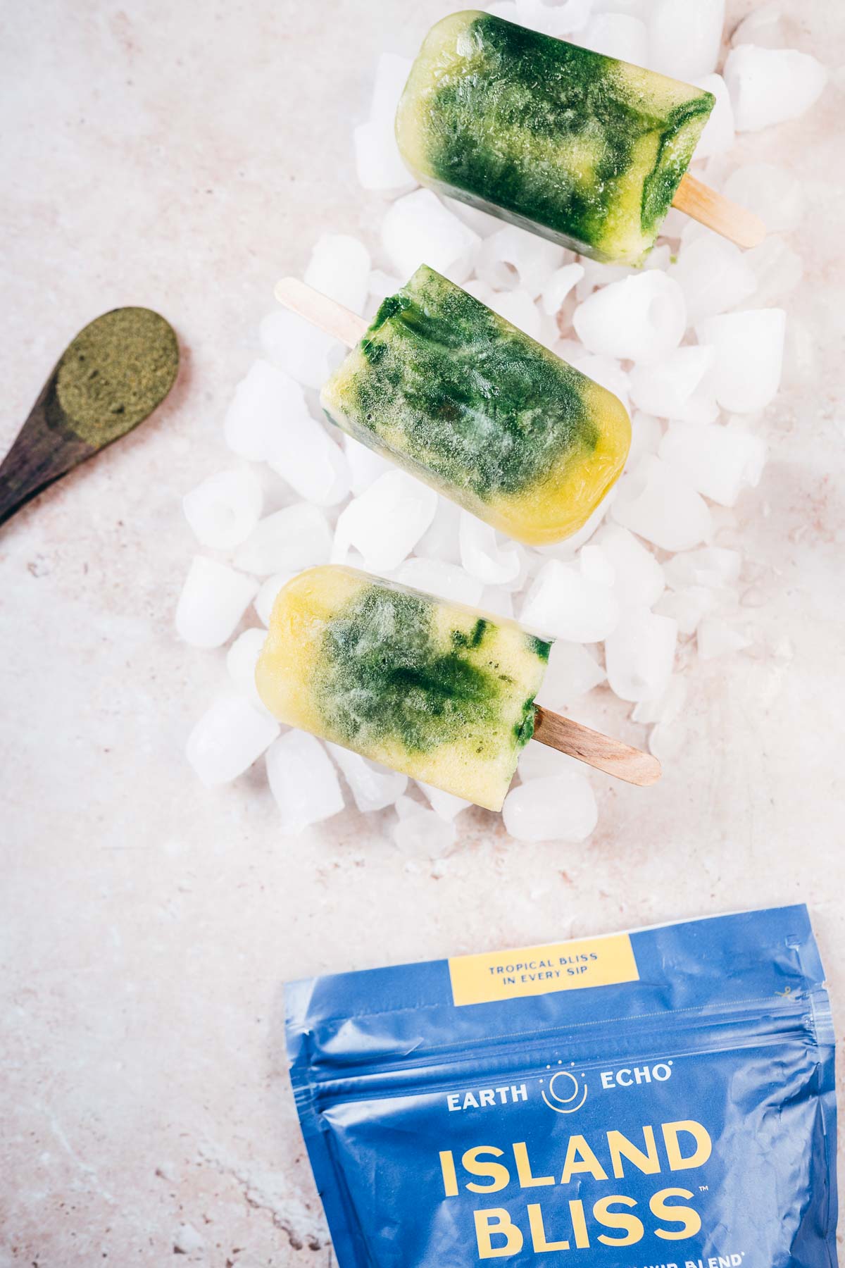 A bag of Earth Echo Island Bliss rests on tan table with multi-colored popsicles.