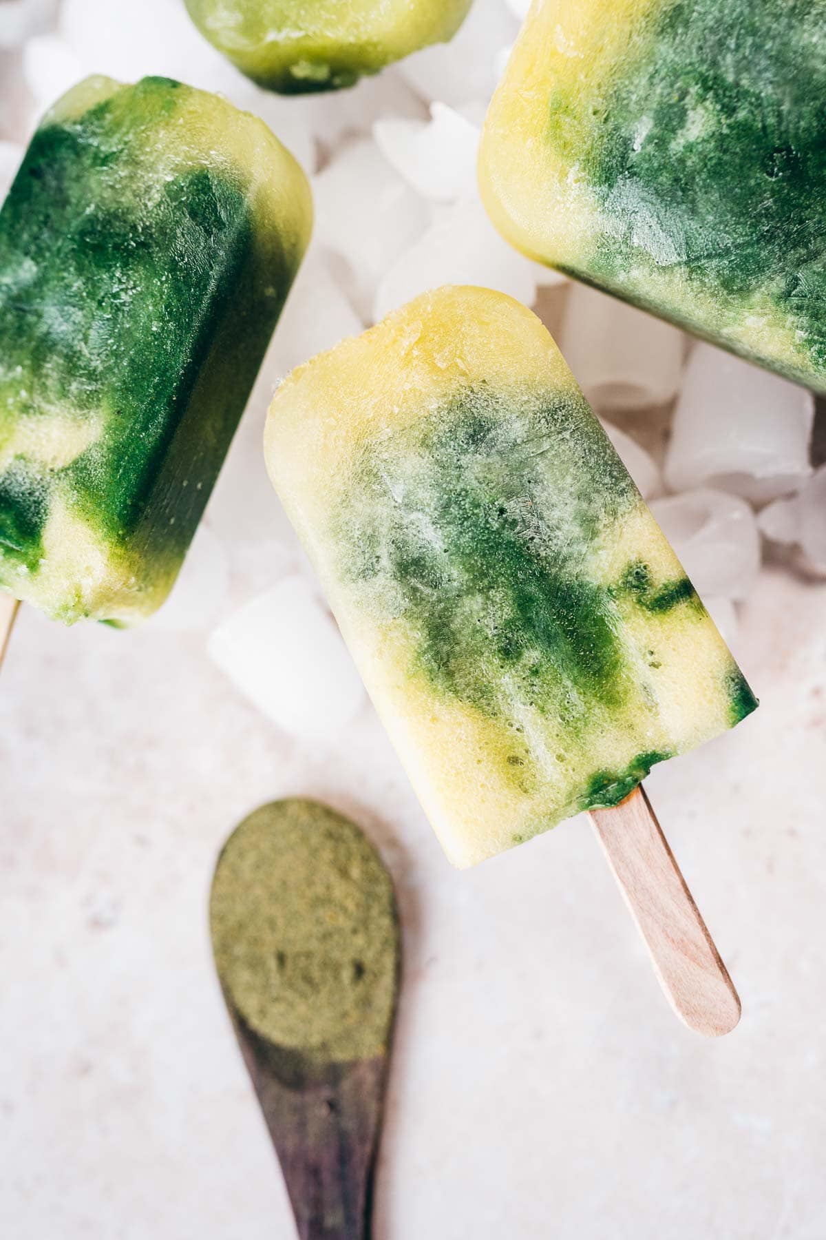 A close shot of a yellow and green popsicle resting on ice.