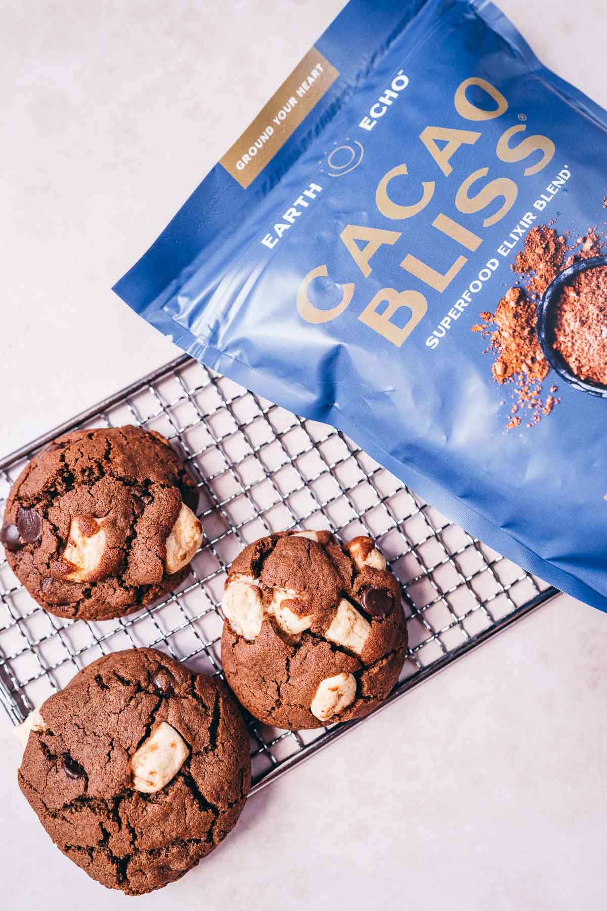 A blue bag of Earth Echo Cacao Bliss rests next to some chocolate marshmallow cookies.