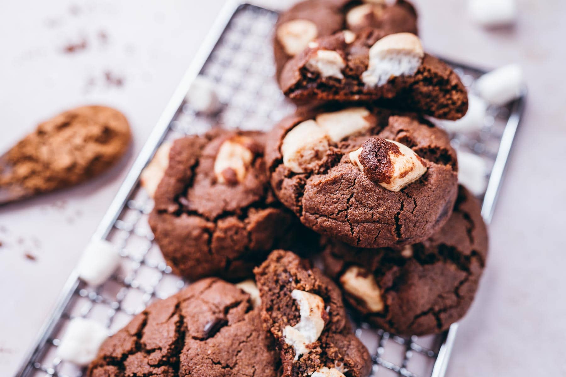 A close shot of chocolate cookies bursting with mini marshmallows.