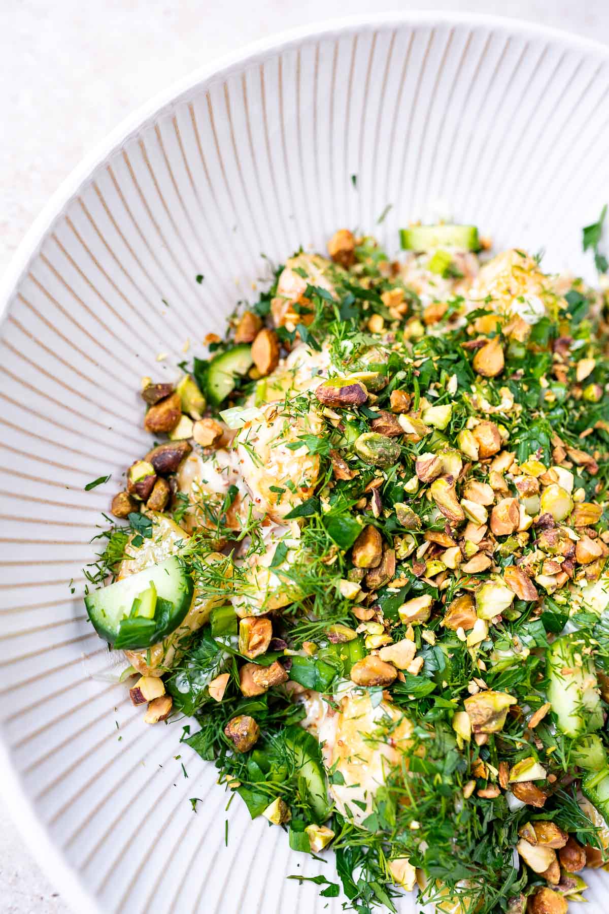 Potatoes topped with fresh green herbs and chopped pistachio nuts.