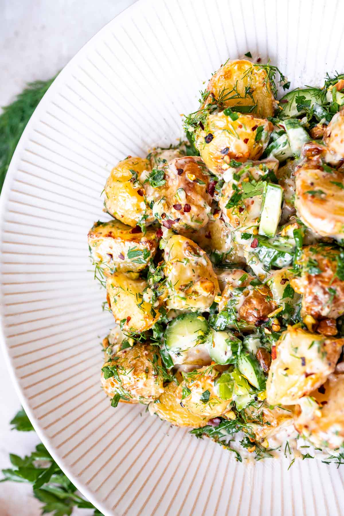 A freshly tossed homemade roasted potato salad in a large white ceramic bowl.