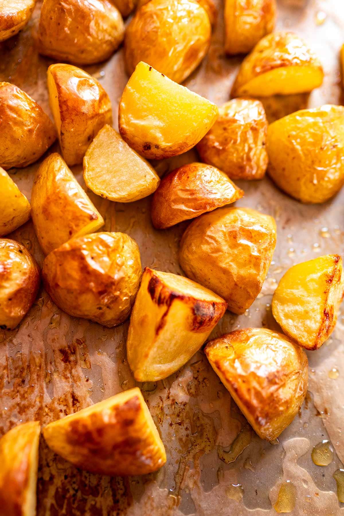 Freshly roasted potatoes on a parchment paper lined baking sheet.