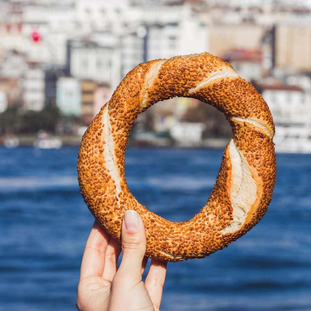 A hand holding a turkish simit.