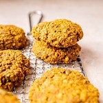 A stack of golden oatmeal cookies on a cooling rack.