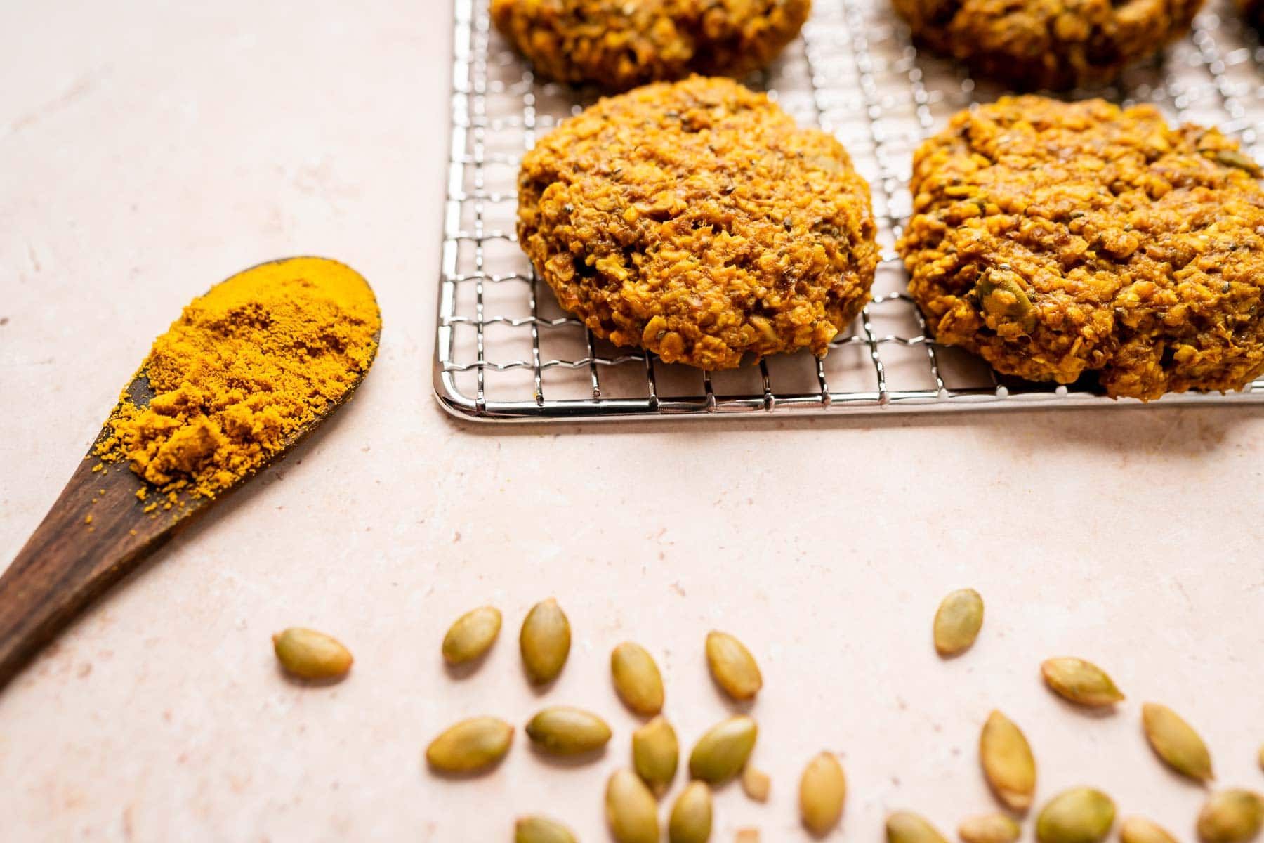 Golden milk cookies on a cooling rack with a wooden spoon.