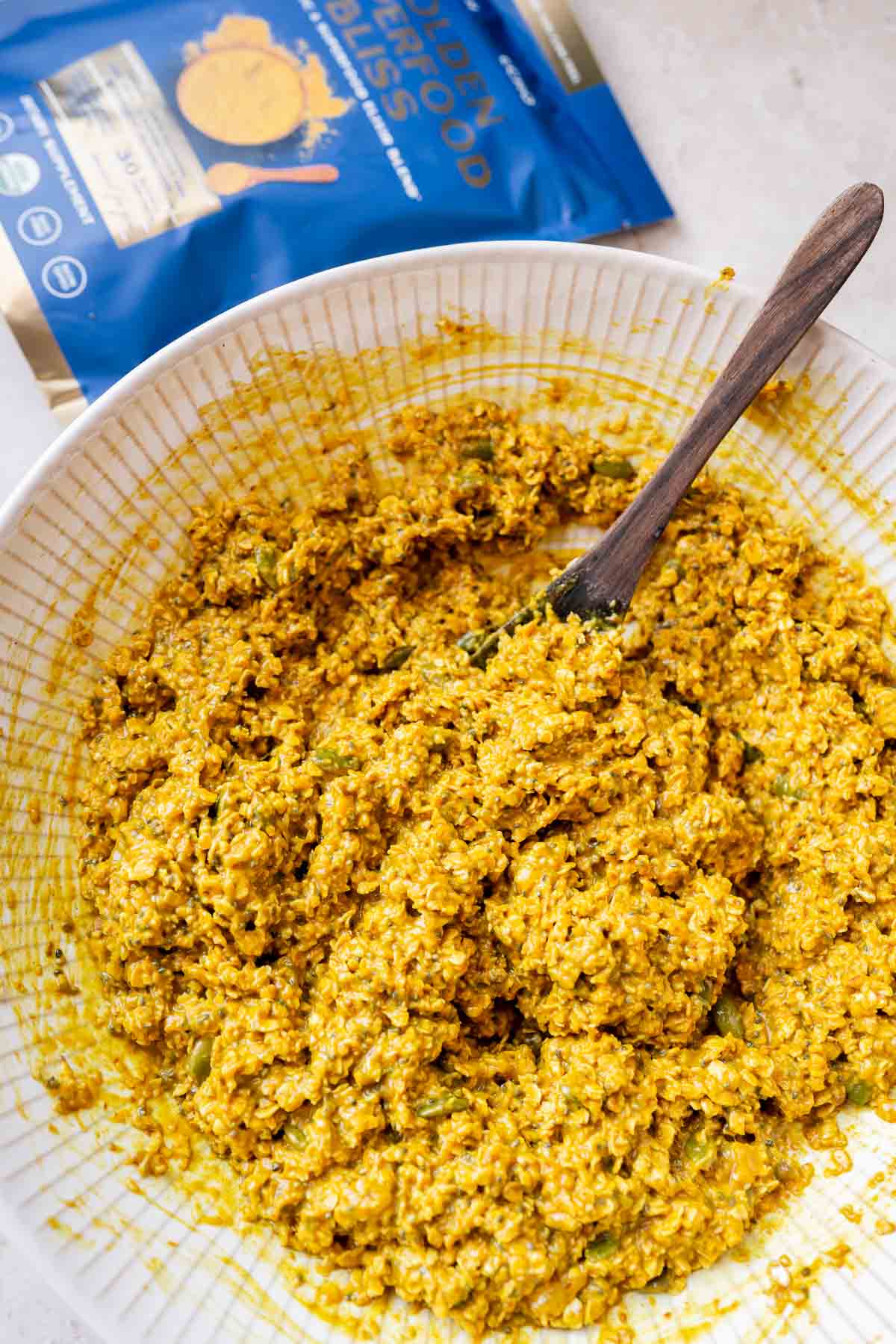 A bowl of golden milk with a spoon next to it.