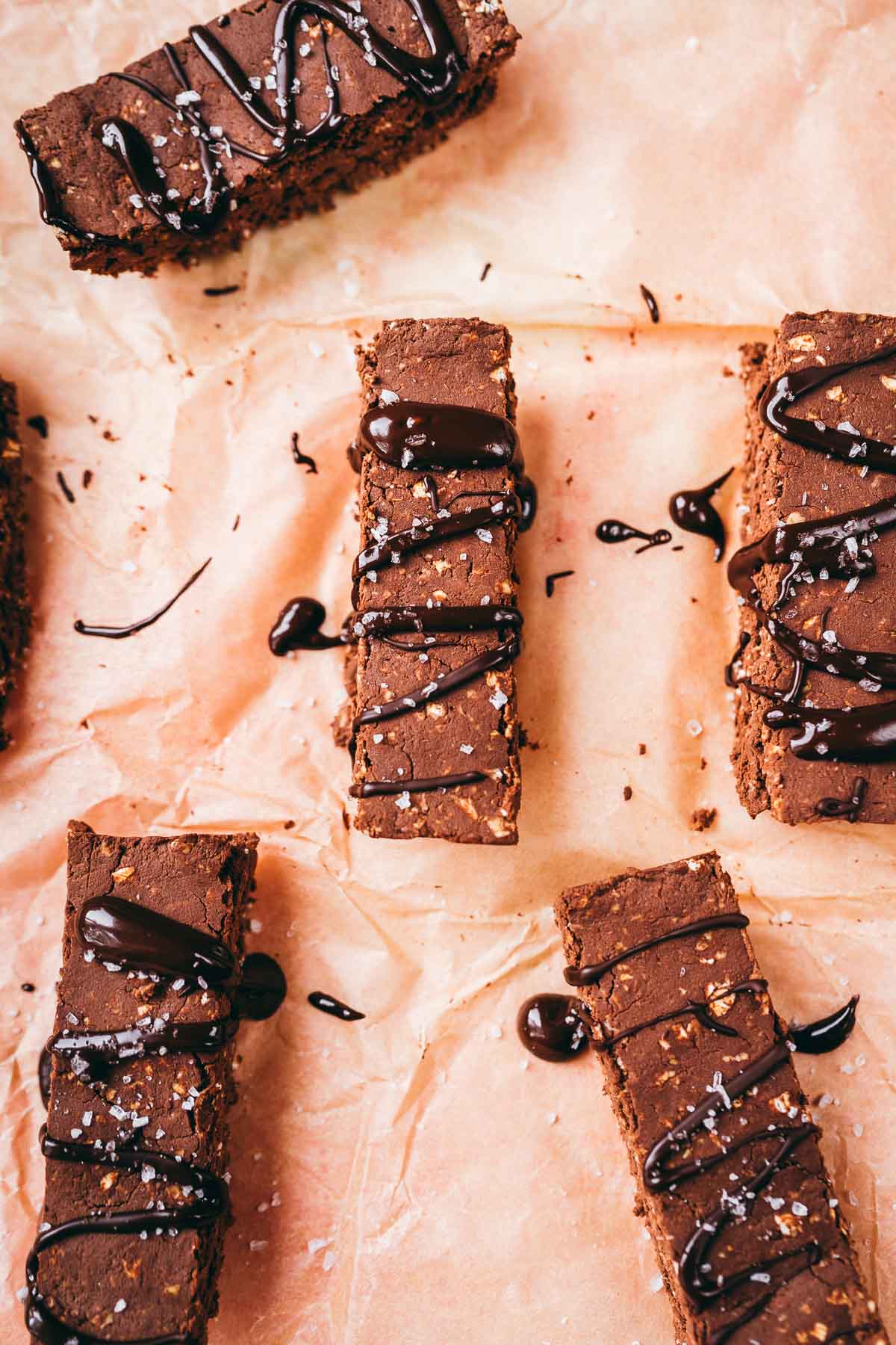 Mocha protein bars drizzled with chocolate and sprinkled with coarse sea salt resting on parchment paper.