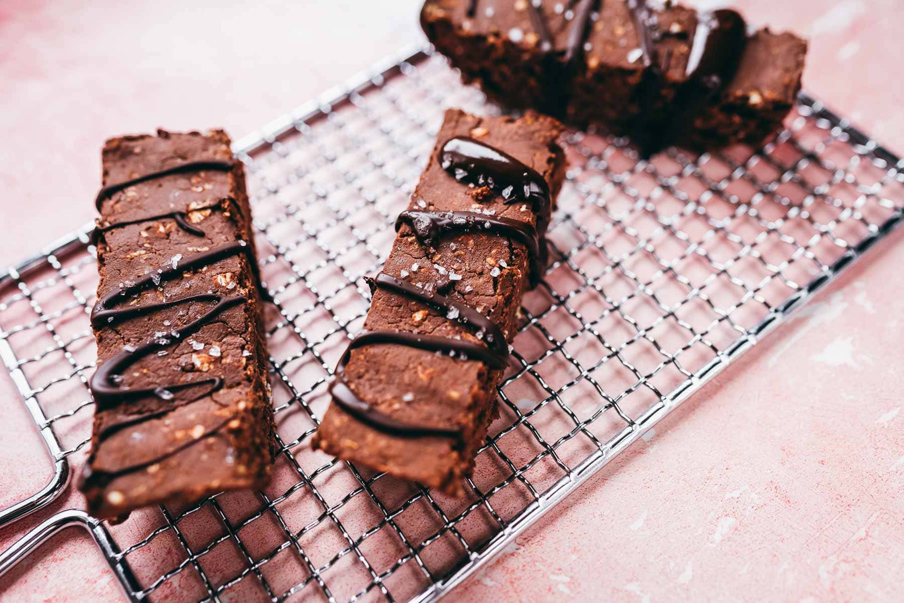 Chocolate protein bars resting on a silver cooling rack.