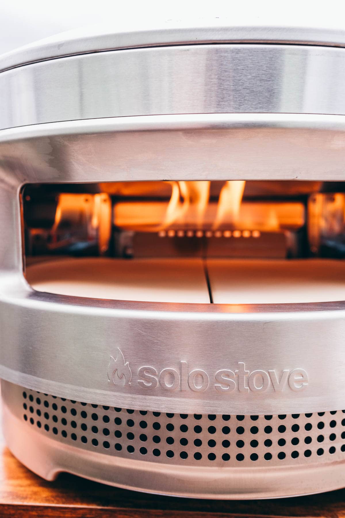 A  solo stove pizza oven with flames coming out of it.