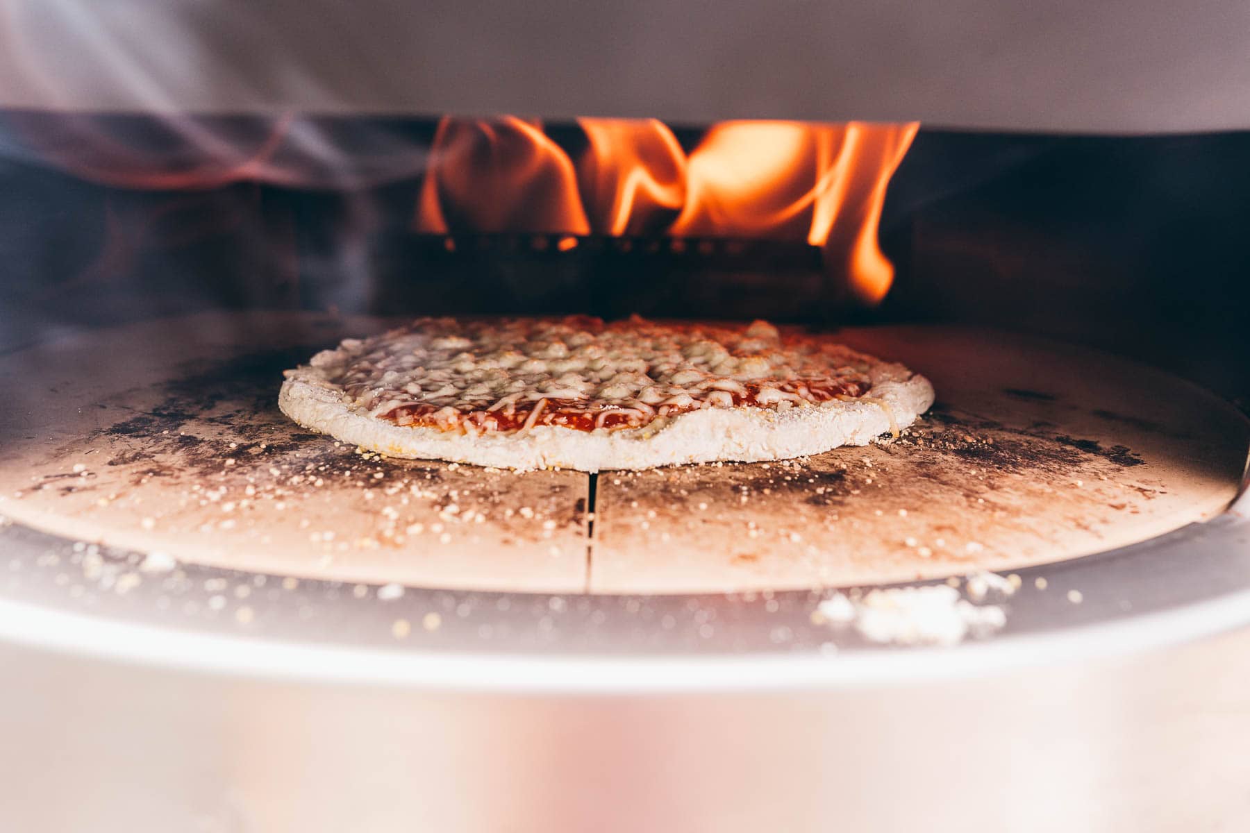 A pizza is being cooked in a solo stove pizza oven.