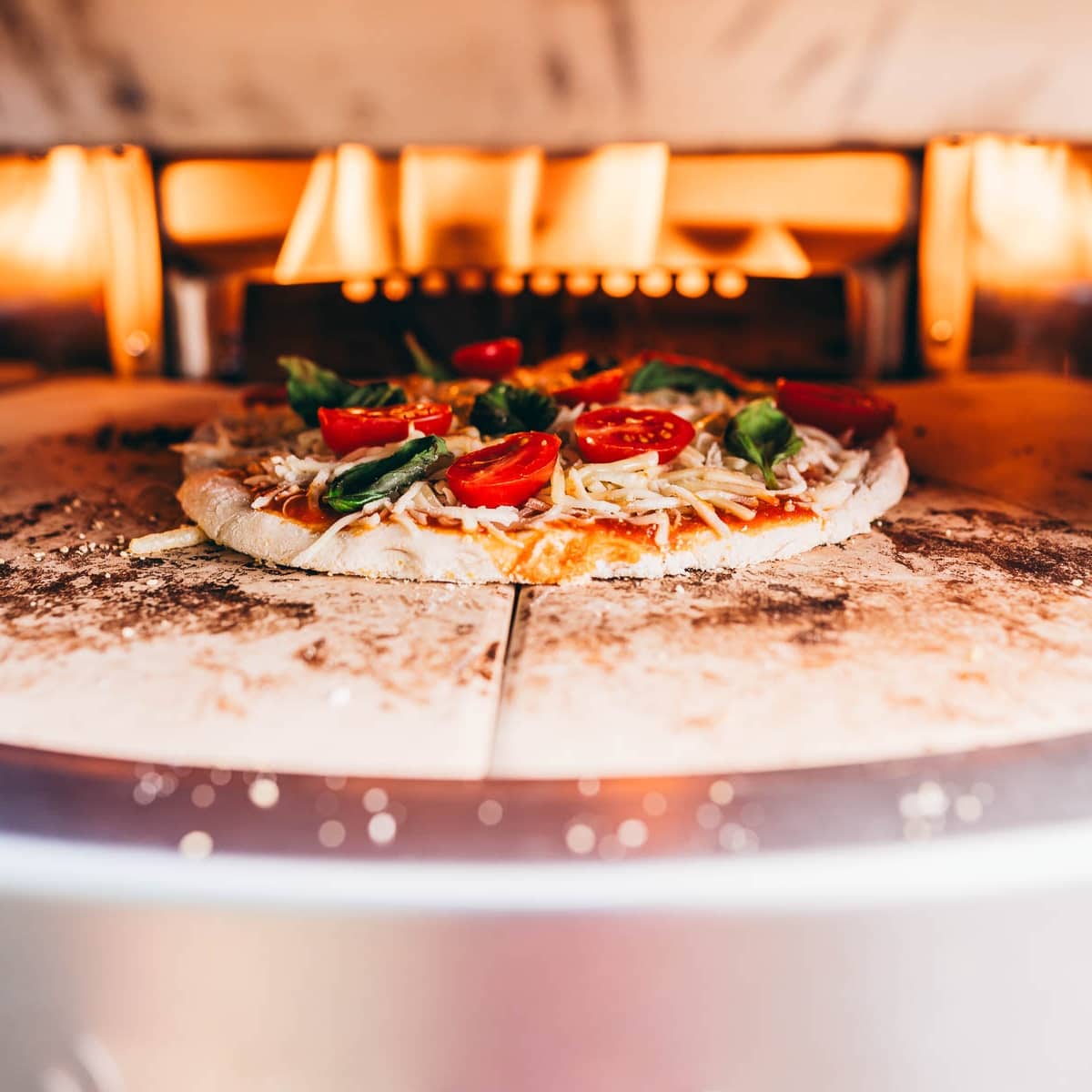 A pizza is being cooked in a solo stove pizza oven.