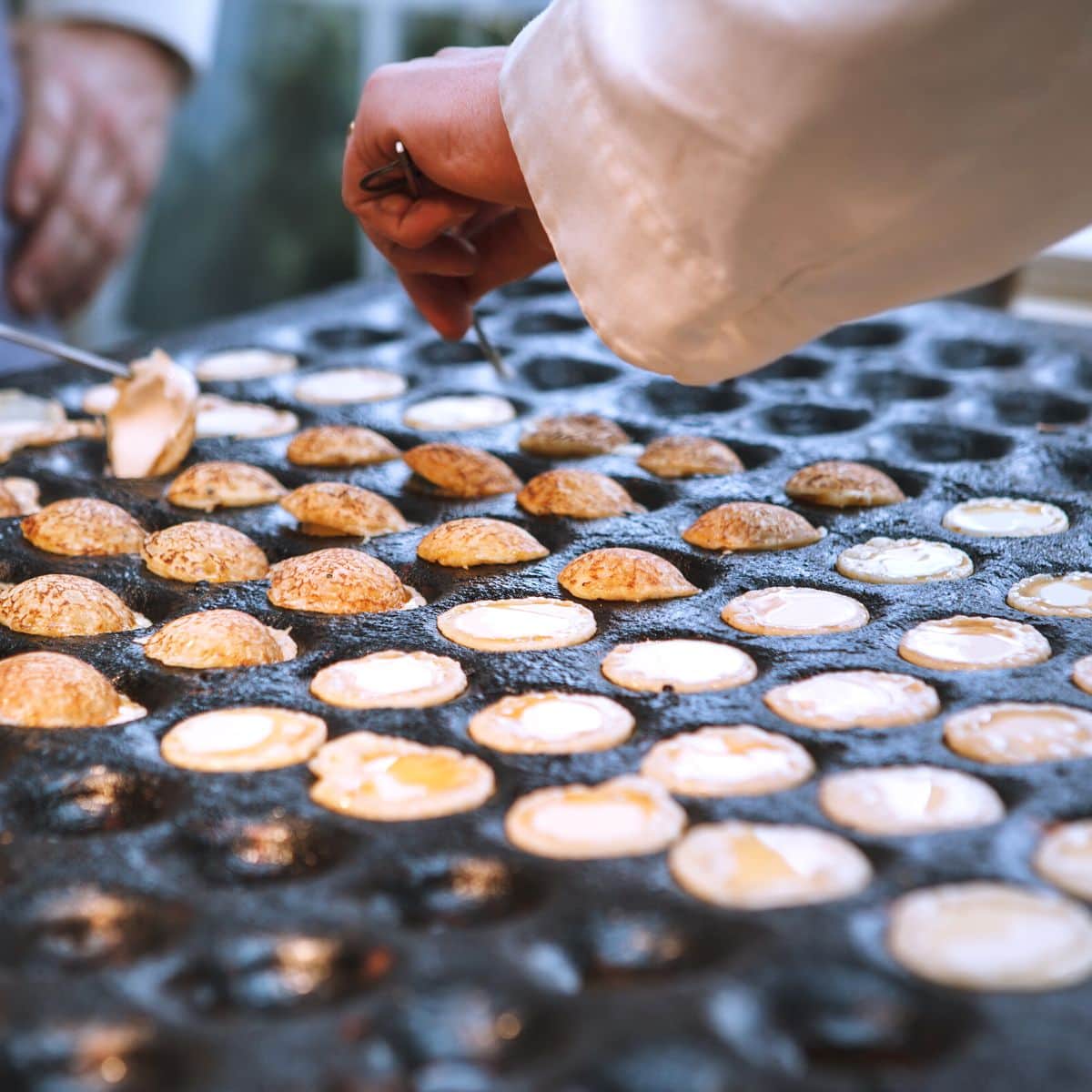 A chef is preparing a tray of vegetarian pastries.