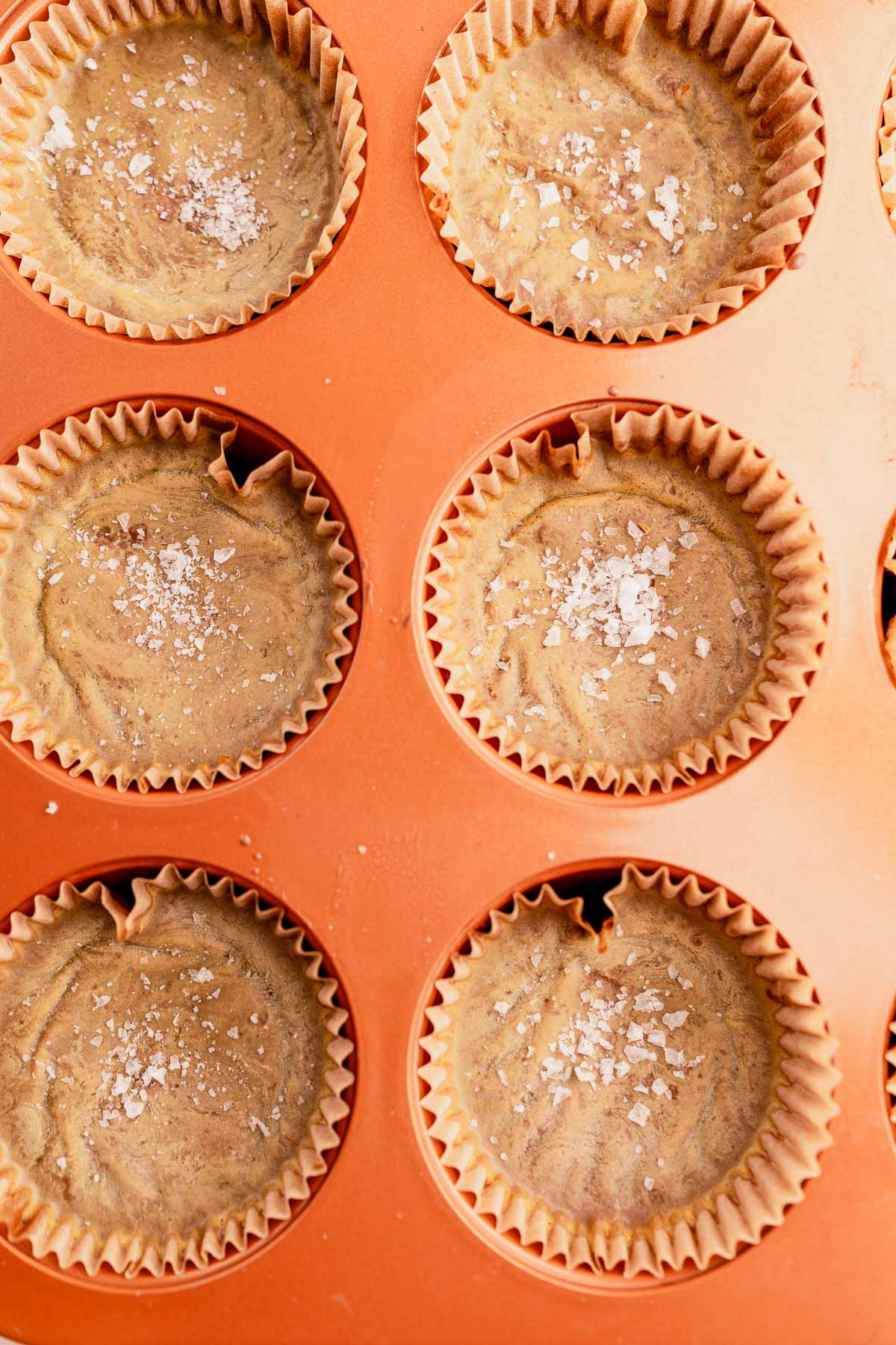 A muffin tin with pumpkin cupcakes in it.